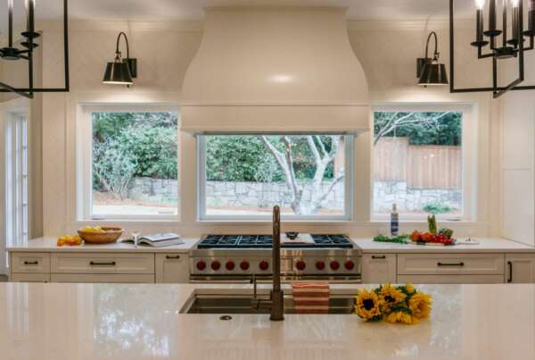 Transitional kitchen design on west paces featuring panoramic windows, undermounted sink, custom range hood, and marble countertops. This kitchen is bright and airy and features our client's beautiful garden.