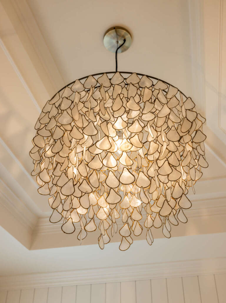 Close-up of nature-inspired capiz shell chandelier with ivory teardrop shell details in the primary bathroom of the Artful Haven luxury home renovation in Suwanee, GA by Infinite Home